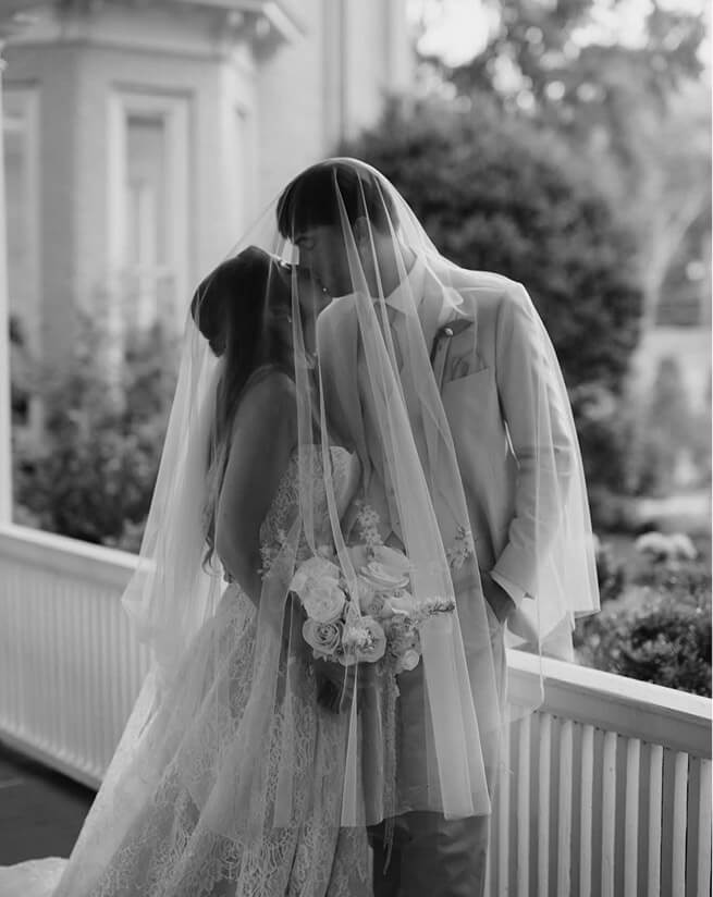 Black and white bride and groom embracing under a veil